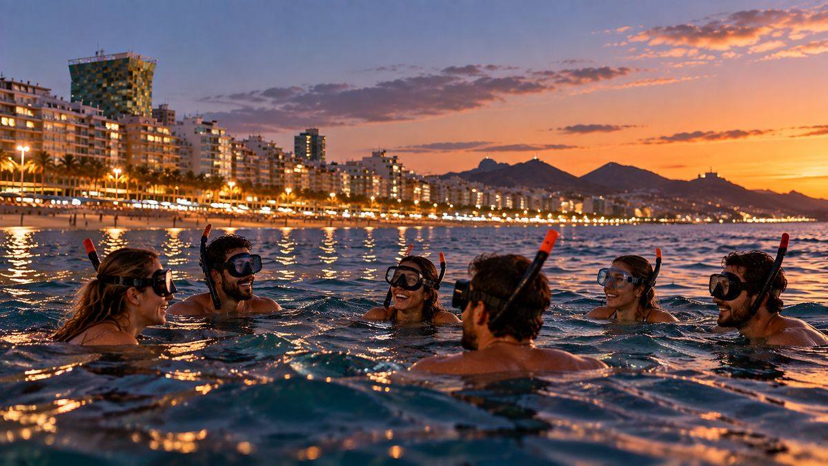 Group snorkelling at dusk with the city lights behind